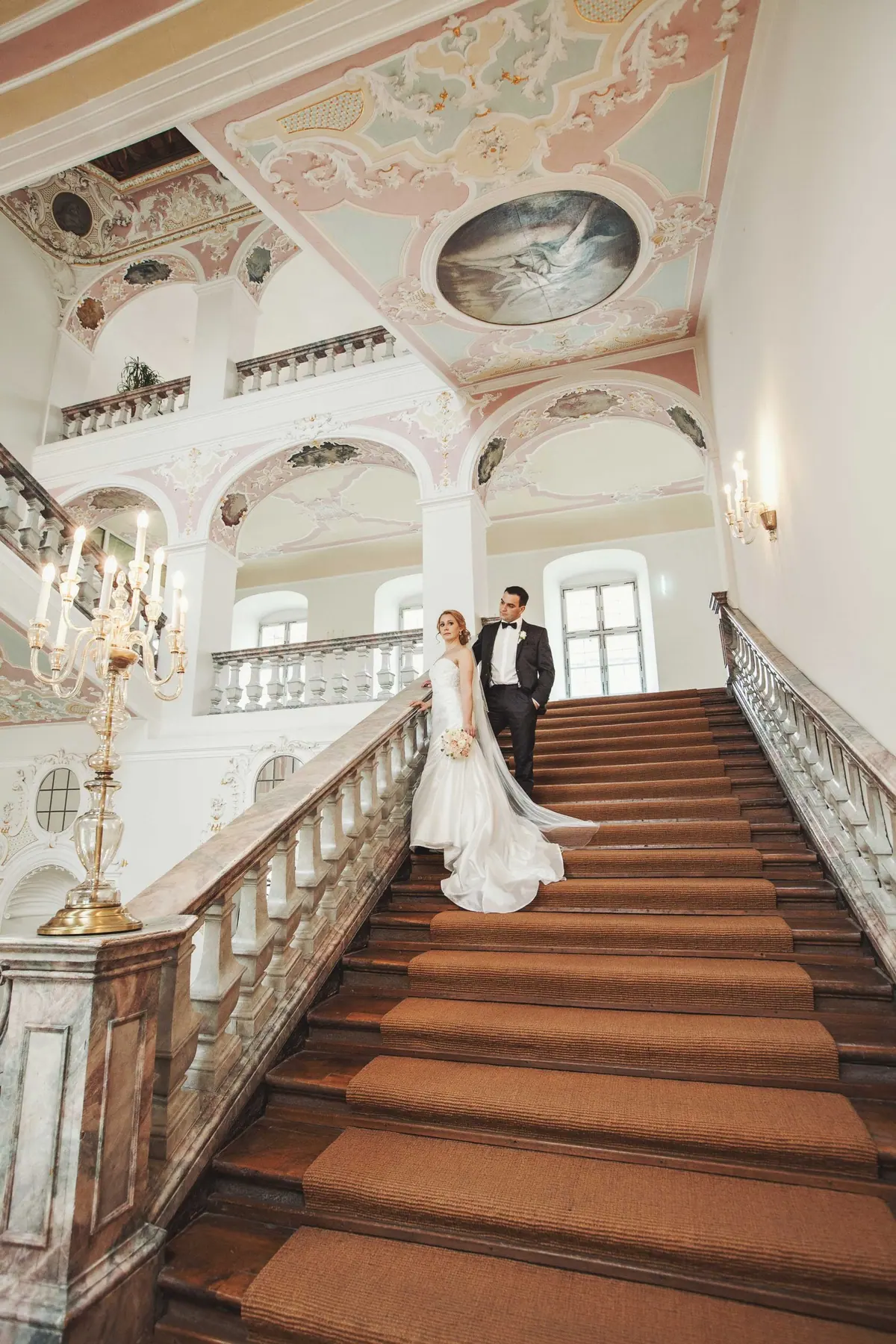 Brautpaar auf der Treppe eines historischen Saals